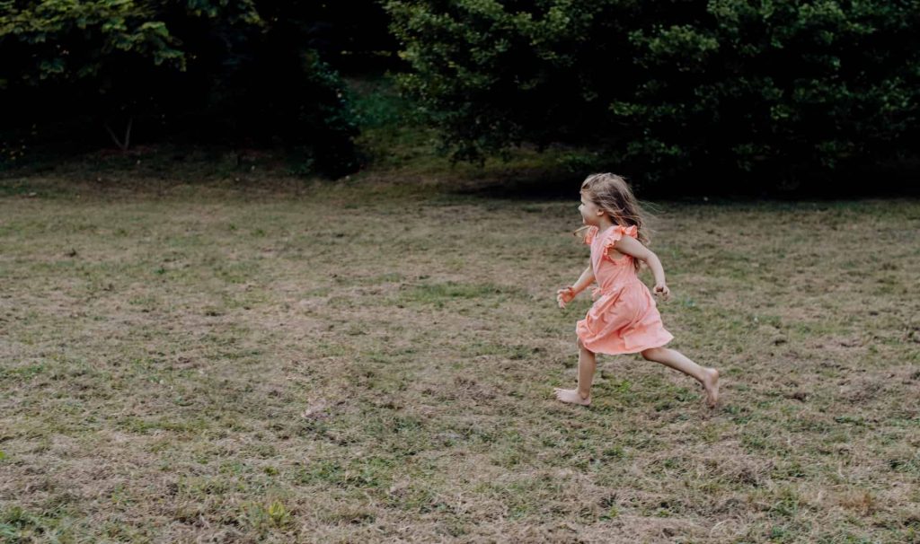 child running barefoot through grass