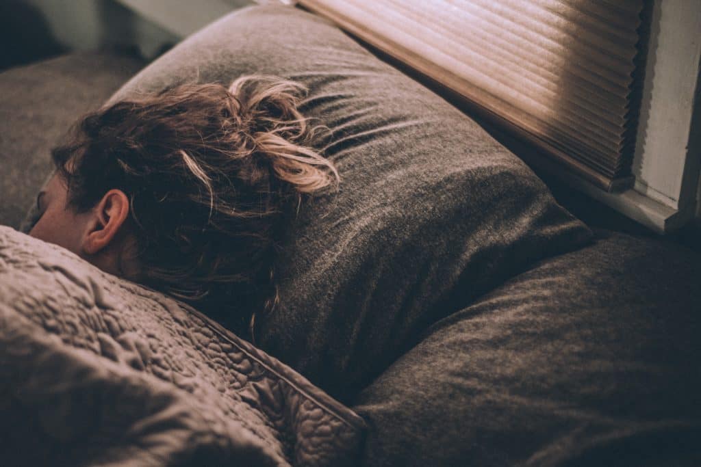 woman sleeping in bed with brown covers