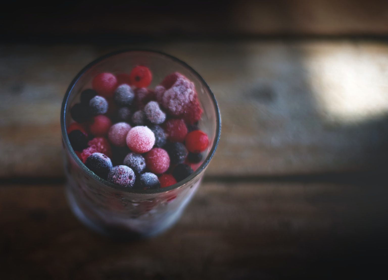 frozen berries in a glass on a wooden table