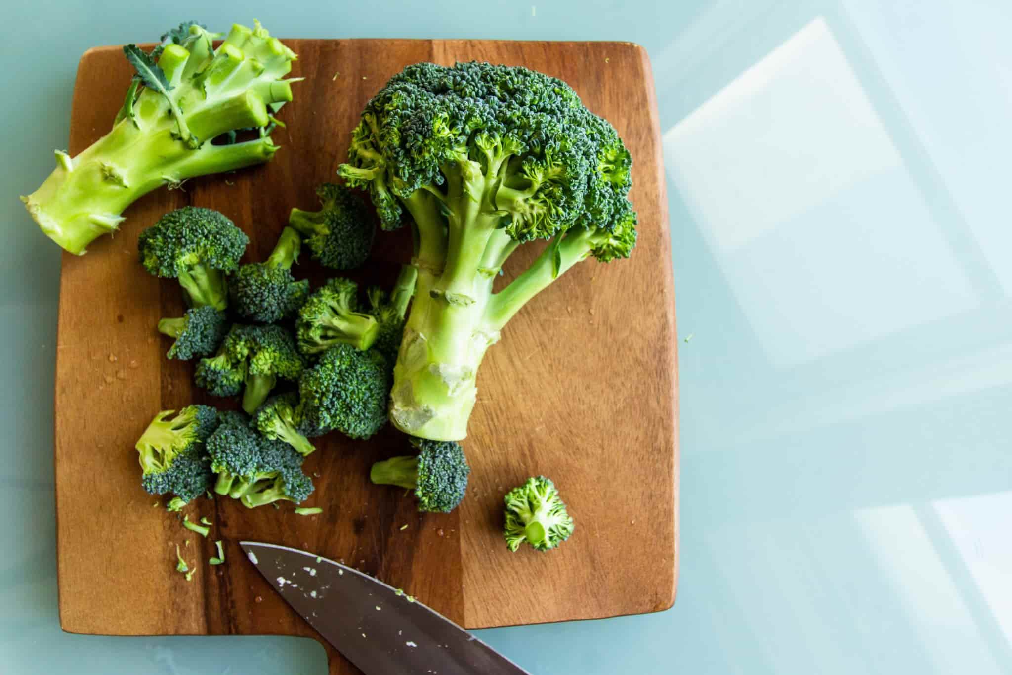 broccoli and a knife on a wooden chopping board
