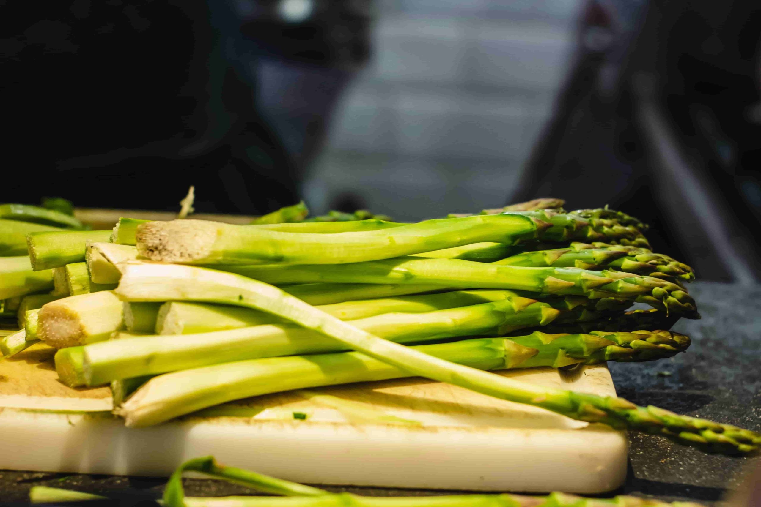asparagus laying on wooden chopping board 