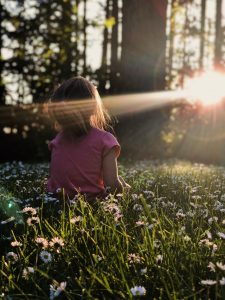 girl sitting in forest amongst flowers