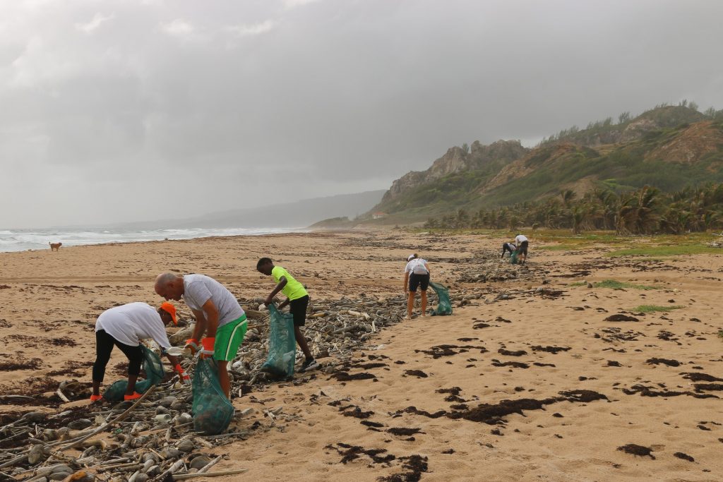 people working together to clean up a littered beach beach