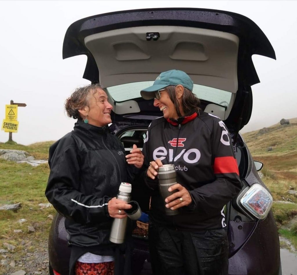 Helene and her friend standing in front of the car smiling at one another 