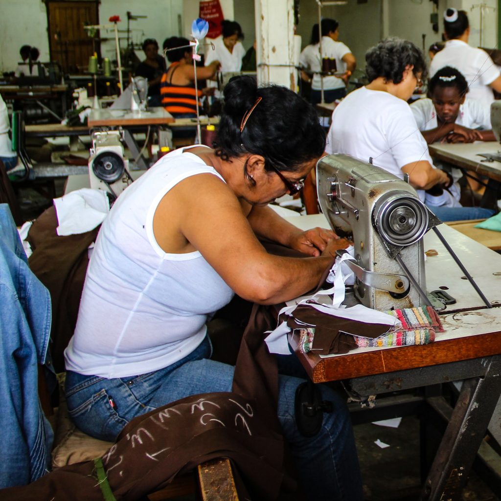 lady wearing a white sleeveless top working on a sewing machine
