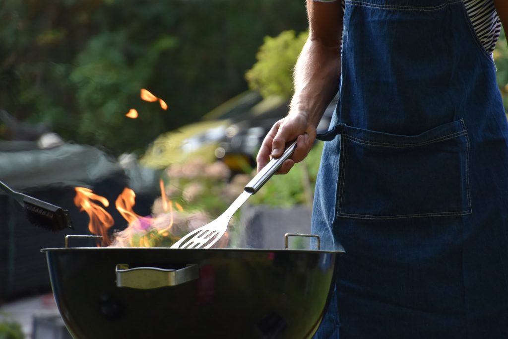 someone holding a BBQ tool into a grill