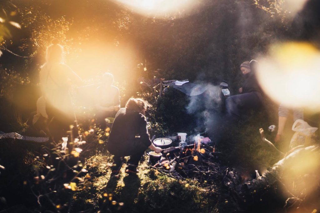 Friluftsliv - a group of friends around a campfire - the photo has some lens flare, suggesting early morning or early evening