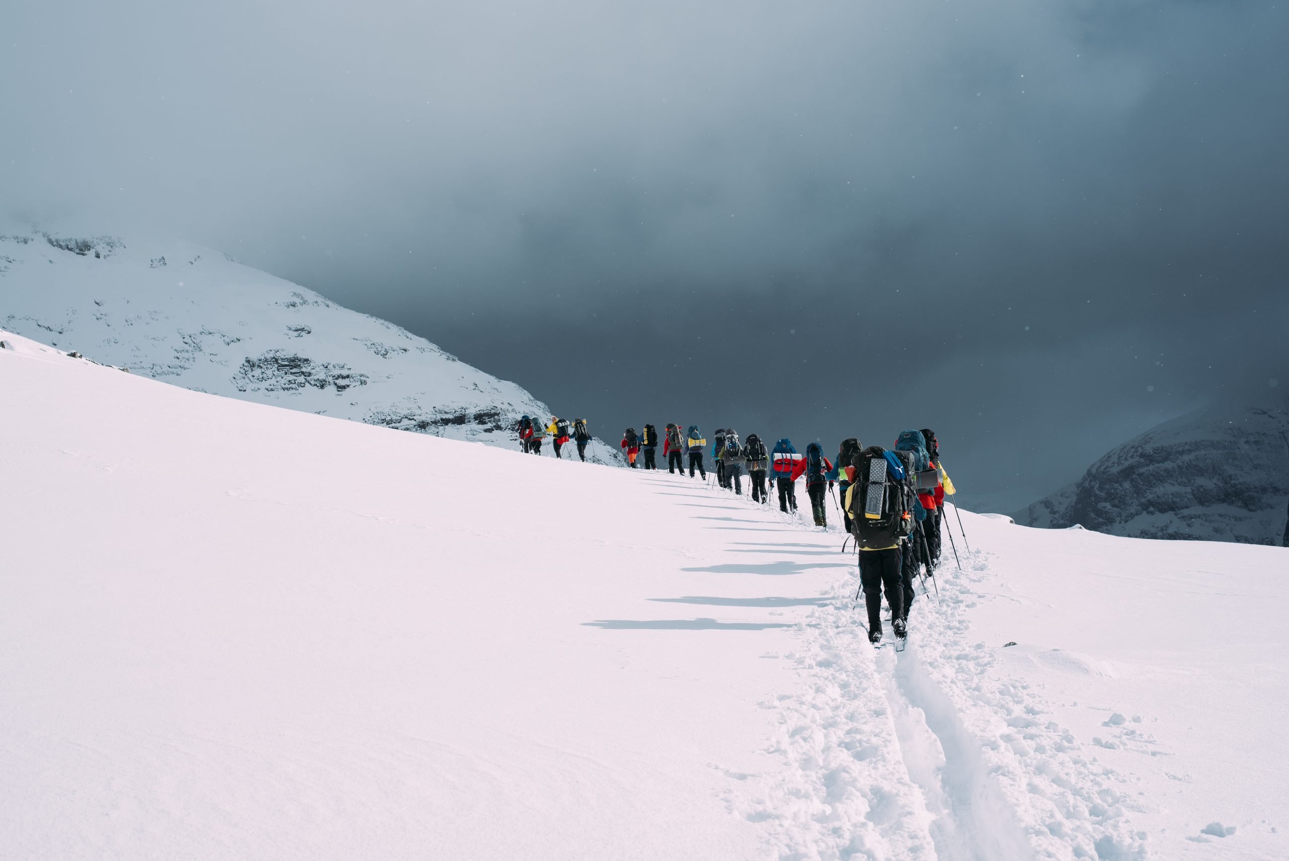 a long line of hikers walking into the distance in the snow