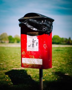red dog poo bin on a field in daytime