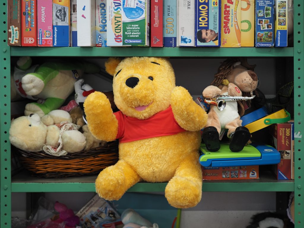  children's toys including a plush Winnie the Pooh on a shelf