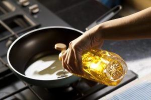 someone pouring cooking oil into a pan