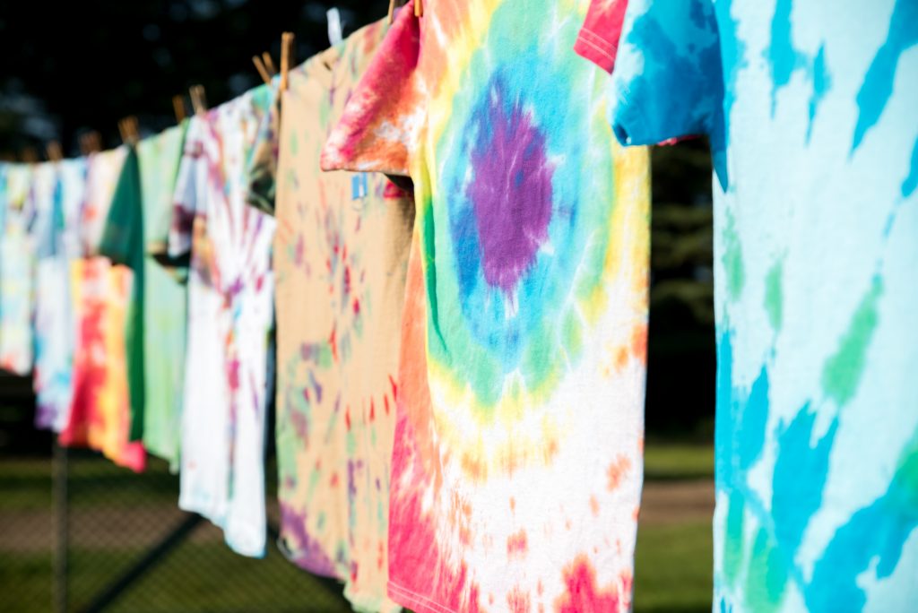 brightly coloured tie-die t shirts hanging out to dry