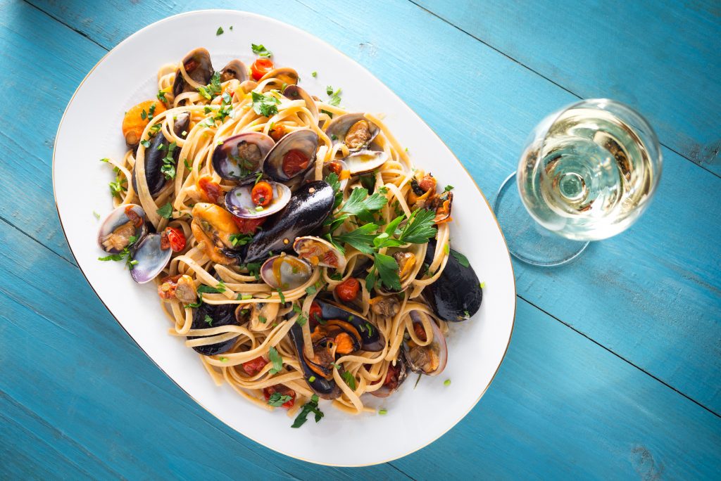 clam linguine on a white plate with blue background